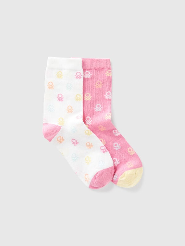 Dos pares de calcetines con logos rosas y blancos. Niño