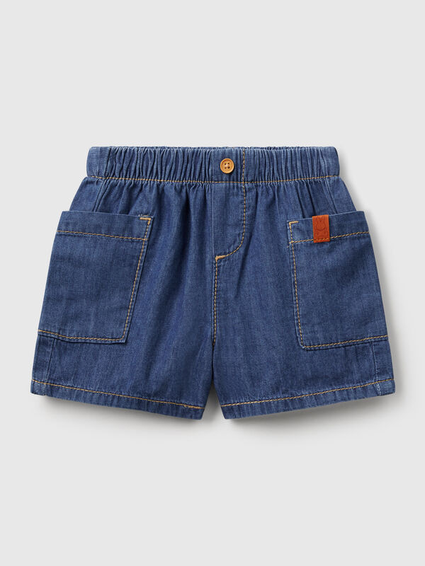 Pantalón corto de cambray de puro algodón. Cintura con elástico interno y falsa solapa con botón efecto madera. Grandes bolsillos aplicados lateralmente. Cómodo y versátil, también se puede combinar con una camisa. Recién nacidos